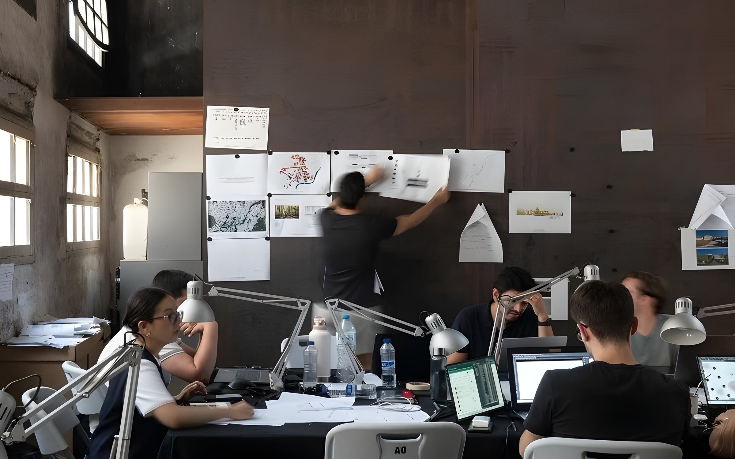 A team at work in a studio, pinning drawings to the wall
