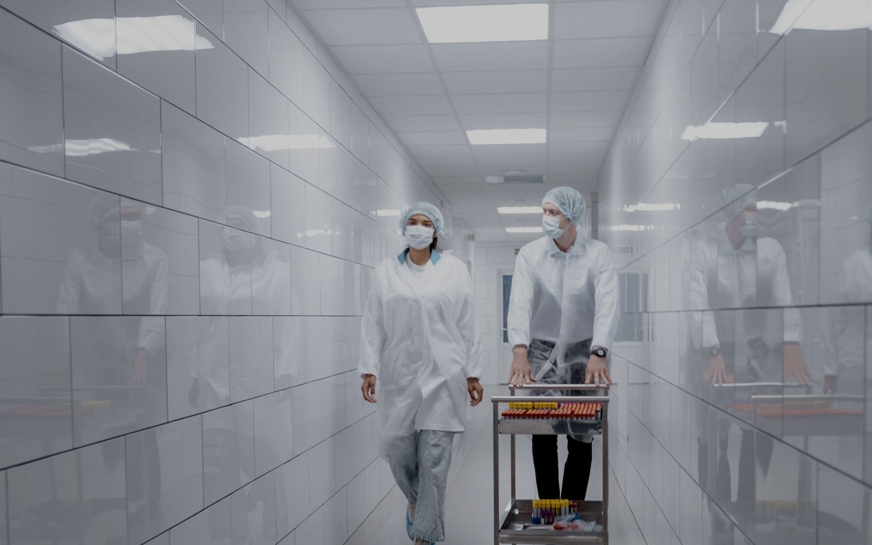 Two lab staff wheeling a trolley of samples down a corridor