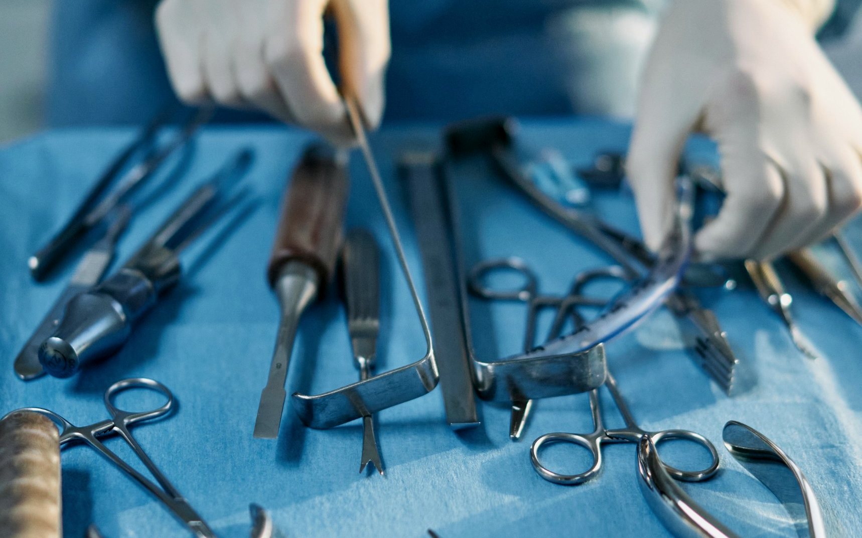 Gloved hands laying out surgical instruments
